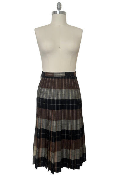 Front view of 1970s vintage reversible black, tan, cream, and green wool plaid pleated midi skirt by Charlotte Ford for Classique Collection, size medium to large. Showing the darker side.