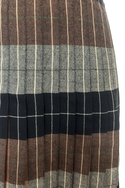 Detail view of 1970s vintage reversible black, tan, cream, and green wool plaid pleated midi skirt by Charlotte Ford for Classique Collection, size medium to large. Showing the pleats sewn down over the hips.