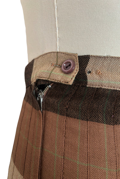 Detail view of 1970s vintage reversible black, tan, cream, and green wool plaid pleated midi skirt by Charlotte Ford for Classique Collection, size medium to large. Showing the Button at the waistband on the lighter side.