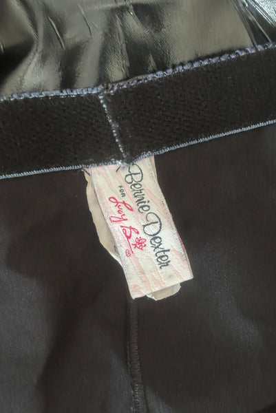 Interior detail view of 2000s vintage goth pin-up black wet look nylon Lycra stretch lingerie garter skirt by Bernie Dexter, size medium to large. Showing a close-up of the plush elastic along the inside edge and the Bernie Dexter for Lucy B label.