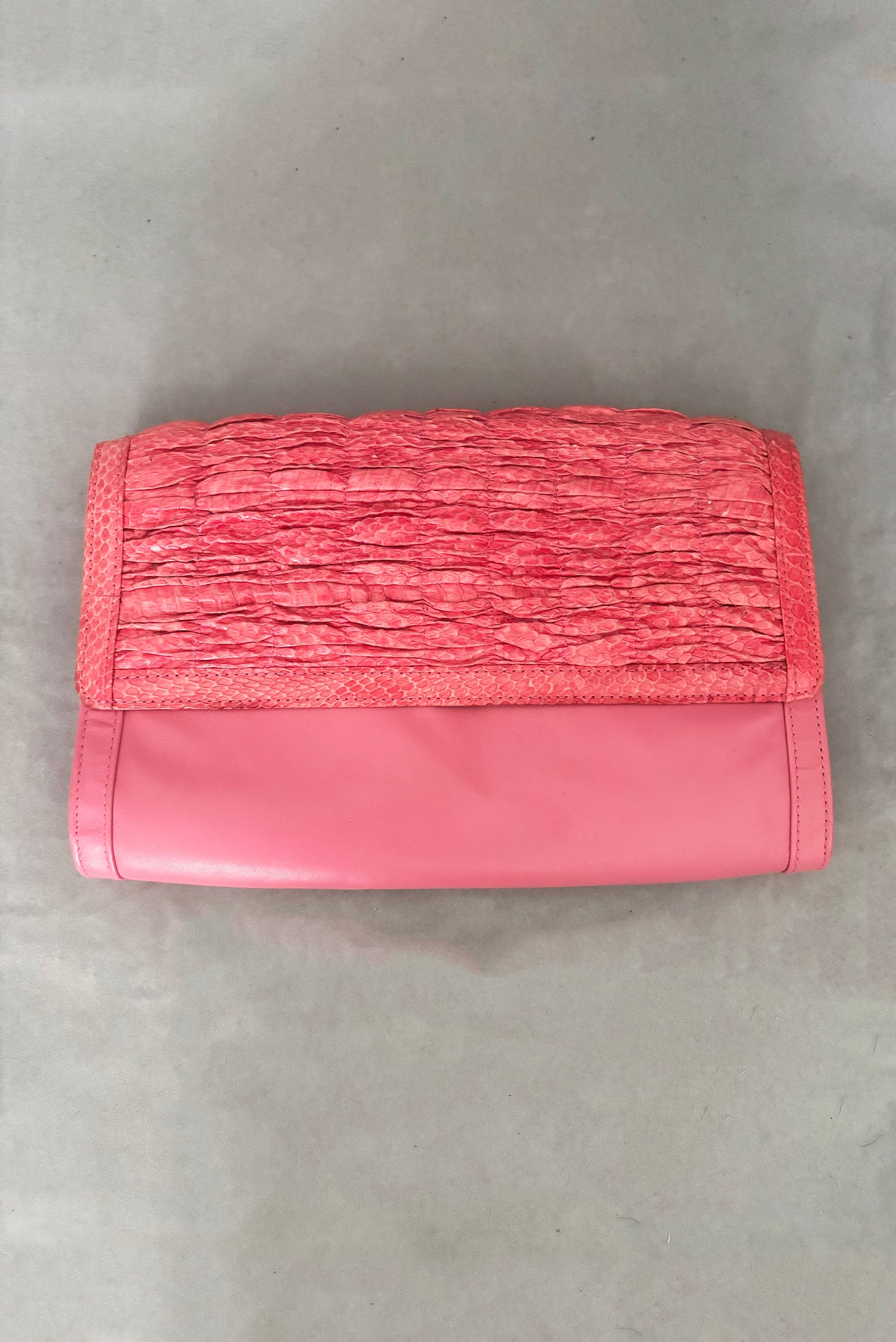 Vertical front view of 1980s vintage pink snakeskin and leather clutch purse with detachable strap by Impo.