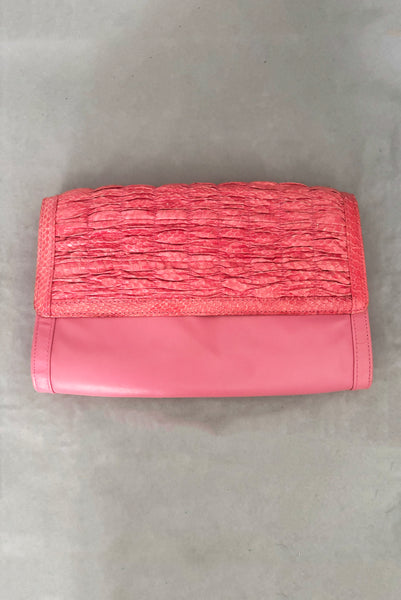 Vertical front view of 1980s vintage pink snakeskin and leather clutch purse with detachable strap by Impo.