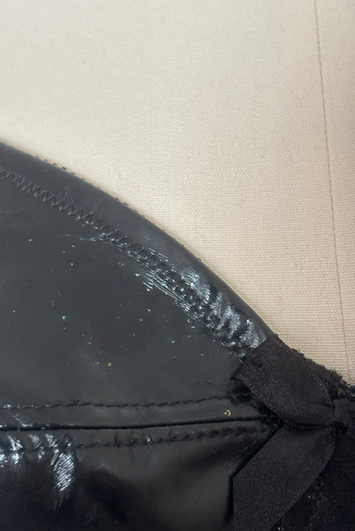 Detail view of 2000s vintage y2k goth pin-up lingerie black nylon Lycra wet look bra by Bernie Dexter for Lucy B, size medium to large. Showing some small piece of glitter stuck to the bra.