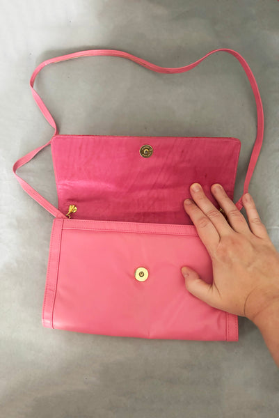 Vertical open view of 1980s vintage pink snakeskin and leather clutch purse with detachable strap by Impo. Showing the gold tone hardware, matching pink satin lining, and detachable shoulder strap.