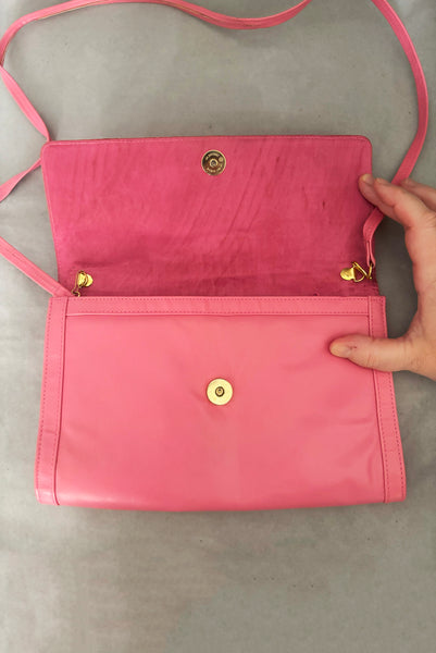 Vertical open view of 1980s vintage pink snakeskin and leather clutch purse with detachable strap by Impo. Showing the gold tone hardware, matching pink satin lining, and detachable shoulder strap.