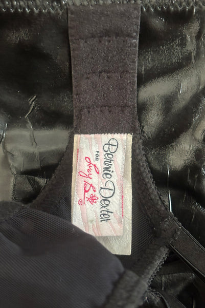 Interior detail view of 2000s vintage y2k goth pin-up lingerie black nylon Lycra wet look bra by Bernie Dexter for Lucy B, size medium to large. Showing a close-up of the Bernie Dexter for Lucy B label.