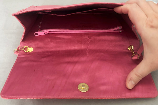 Horizontal open view of 1980s vintage pink snakeskin and leather clutch purse with detachable strap by Impo. Showing the gold tone hardware, matching pink satin lining, and side pocket with zipper.