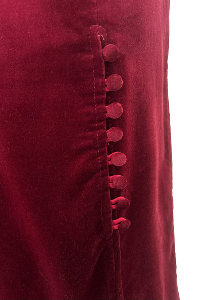 Detail view of 1970s vintage burgundy velveteen button front pencil skirt, size medium to large. Showing a close up of the front slit with self covered buttons and matching satin button loops.