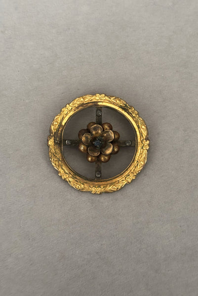 Vertical front view of 1920s to 1930s vintage early White Co delicate round floral gold filled brooch with blue rhinestone center.