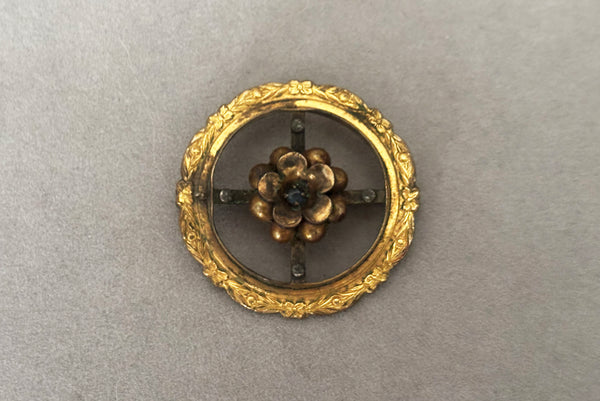 Horizontal front view of 1920s to 1930s vintage early White Co delicate round floral gold filled brooch with blue rhinestone center.