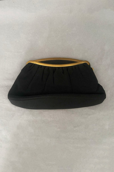 Vertical front view of 1950s vintage black faille gold tone metal frame side clasps clutch handbag.