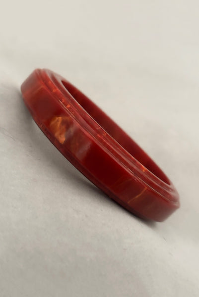 Vertical perspective view of 1940s vintage groove carved rust and yellow marbled Bakelite bangle bracelet.