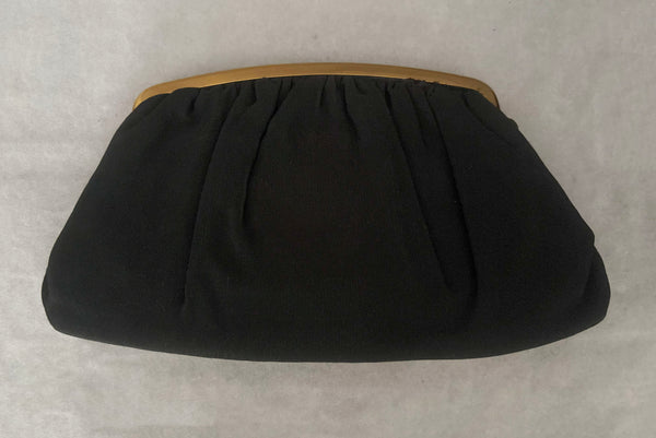 Horizontal back view of 1950s vintage black faille gold tone metal frame side clasps clutch handbag.