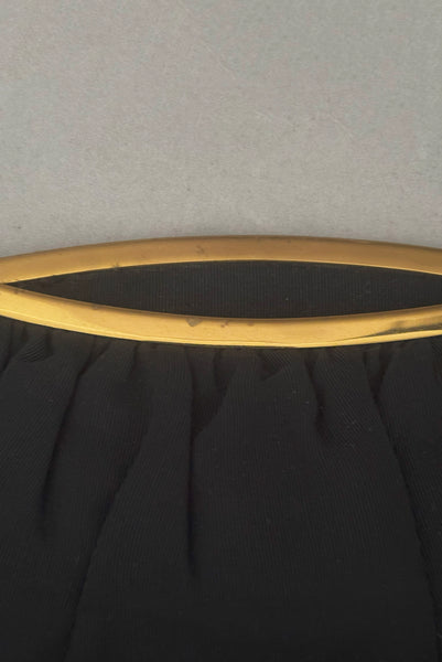 Detail view of 1950s vintage black faille gold tone metal frame side clasps clutch handbag. Showing wear to the gold tone frame.