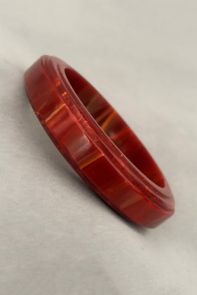 Vertical perspective view of 1940s vintage groove carved rust and yellow marbled Bakelite bangle bracelet.