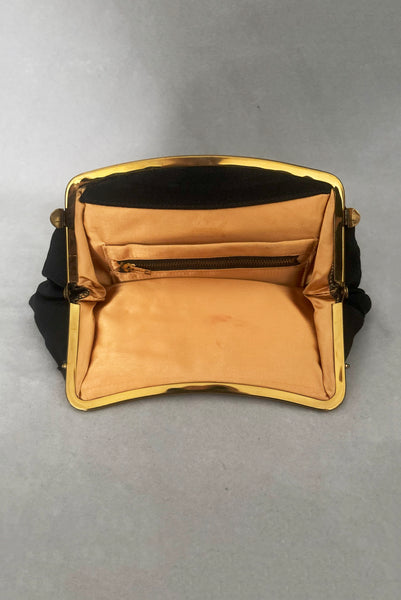 Vertical interior view of 1950s vintage black faille gold tone metal frame side clasps clutch handbag. Showing the peach satin lining.