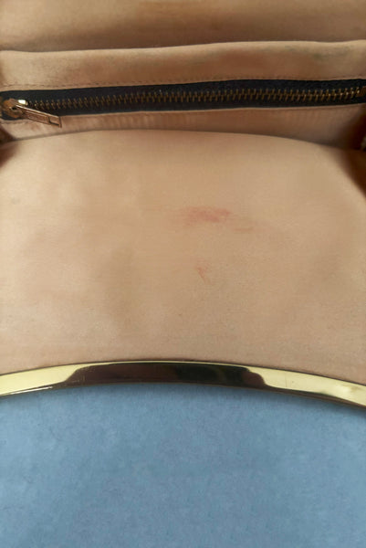 Interior detail view of 1950s vintage black faille gold tone metal frame side clasps clutch handbag. Showing a lipstick stain on the peach satin lining.