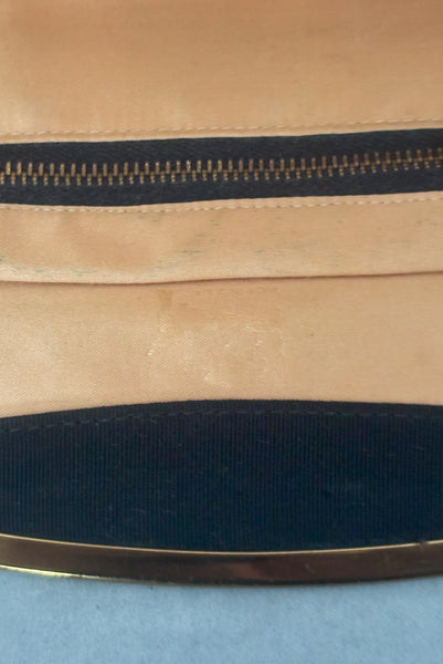 Interior detail view of 1950s vintage black faille gold tone metal frame side clasps clutch handbag. Showing the faded stamp.