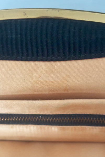 Interior detail view of 1950s vintage black faille gold tone metal frame side clasps clutch handbag. Showing the faded stamp.