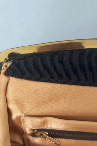 Interior detail view of 1950s vintage black faille gold tone metal frame side clasps clutch handbag. Showing where the fabric has slipped out of the frame. 