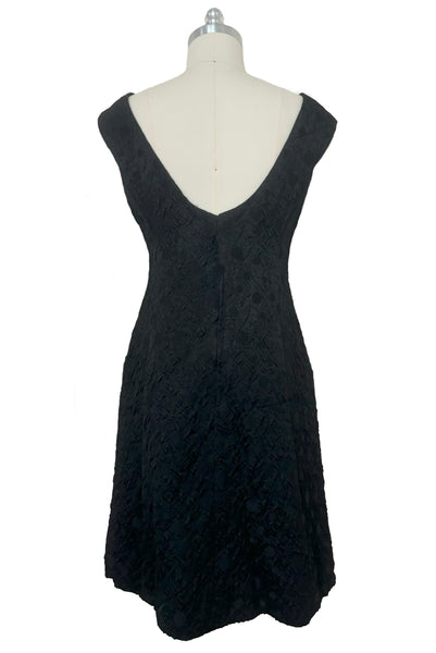 Back view of 1960s vintage black matelassé jacquard Mod cocktail dress and red satin lined wrap, size medium to large.
