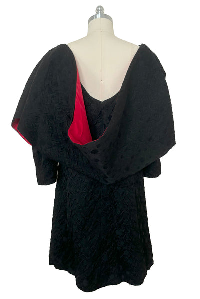 Back view of 1960s vintage black matelassé jacquard Mod cocktail dress and red satin lined wrap, size medium to large.