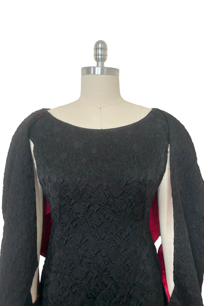 Bodice front view of 1960s vintage black matelassé jacquard Mod cocktail dress and red satin lined wrap, size medium to large.