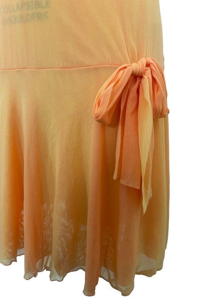 Detail view of 2000s y2k vintage as is pink floral embroidered orange and peach drop waist mesh Enya Chemise by Cosabella, size large to extra large. Showing the hip bow at the drop waist and the significant sun fading.