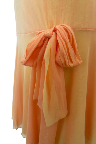 Detail view of 2000s y2k vintage as is pink floral embroidered orange and peach drop waist mesh Enya Chemise by Cosabella, size large to extra large. Showing the hip bow at the drop waist and the significant sun fading.