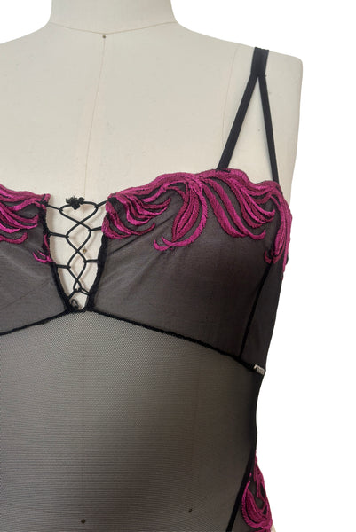 Detail view of 1990s vintage black and fuchsia pink embroidered sheer mesh high cut throng bodysuit by Extreme, size medium to large. Showing the scalloped embroidery and lacing detail at bust.