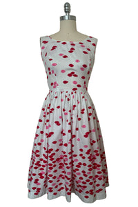 Front view of 1950s vintage red and pink lips novelty border print white cotton sleeveless, full gathered skirt dress, size extra small to small.