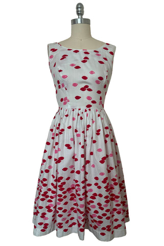 Front view of 1950s vintage red and pink lips novelty border print white cotton sleeveless, full gathered skirt dress, size extra small to small.