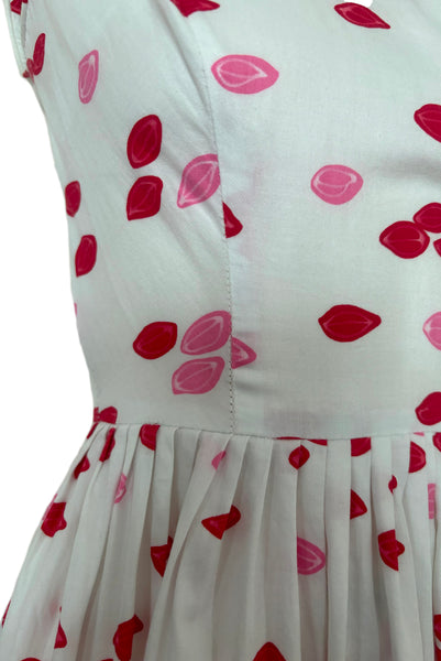 Detail of 1950s vintage red and pink lips novelty border print white cotton sleeveless, full gathered skirt dress, size extra small to small. Showing stress at the bodice seams.