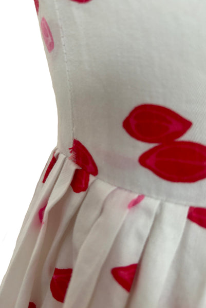Detail of 1950s vintage red and pink lips novelty border print white cotton sleeveless, full gathered skirt dress, size extra small to small. Showing stress at the bodice seams.