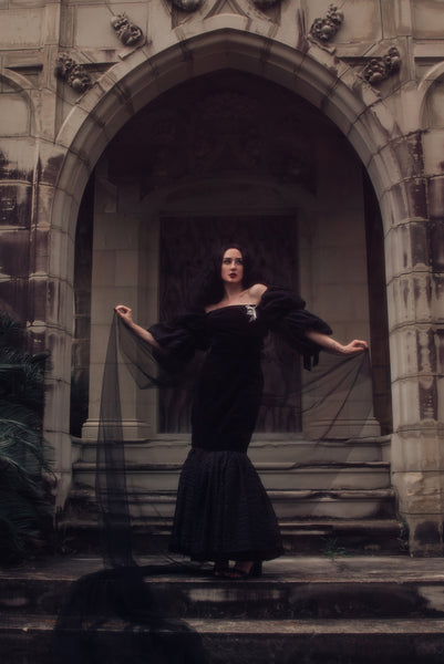 Portrait view on model in a cemetery. Black wedding dress.  1980s vintage Barboglio black velveteen and windowpane organza mermaid evening gown with puff sleeves, small to medium.