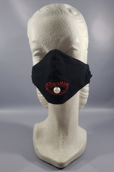 The Leslie Courreges Elsa Face Mask features a glass bead and faux pearl embellishment for a surreal addition to a practical black cotton face mask.