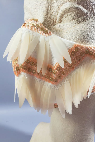 The Leslie Courreges Eleanor Mask features gold sequins against blush embroidery with ivory fringe sequins.