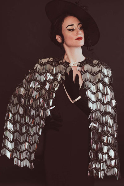 The Leslie Courreges Eleanor Cape features black sequins against complementary embroidery with silver fringe sequins.