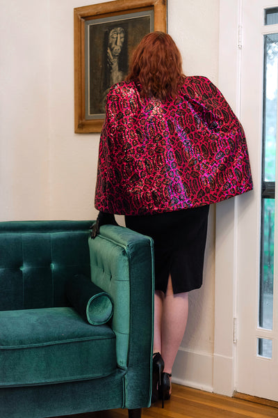 The Leslie Courreges Davis Cape takes the perfect fitted cape silhouette and adds a flourish with a pink sequin animal print.